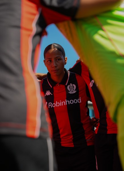 Joueuse en maillot rouge et noir, portrait entre deux coéquipières