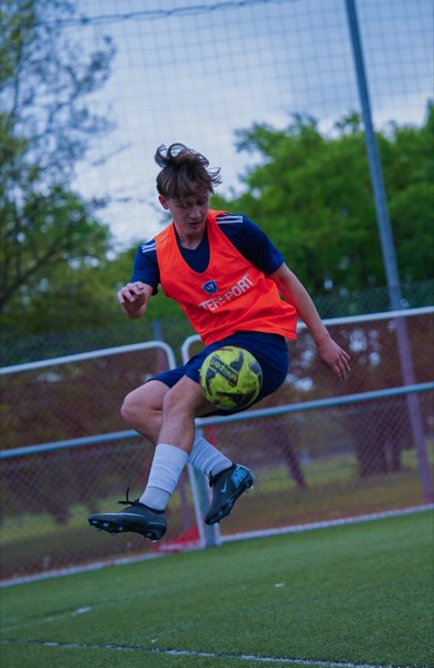 Jeune joueur suspendu en l'air en train de contrôler un ballon