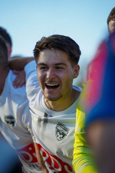Joueur souriant, maillot Craponne, câlin collectif après un but